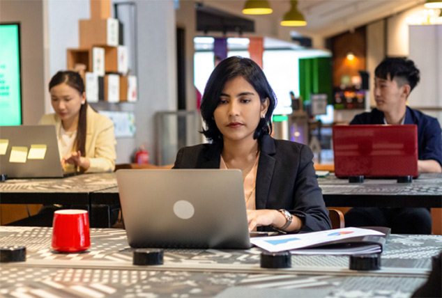 Woman works on her laptop at desk late at night